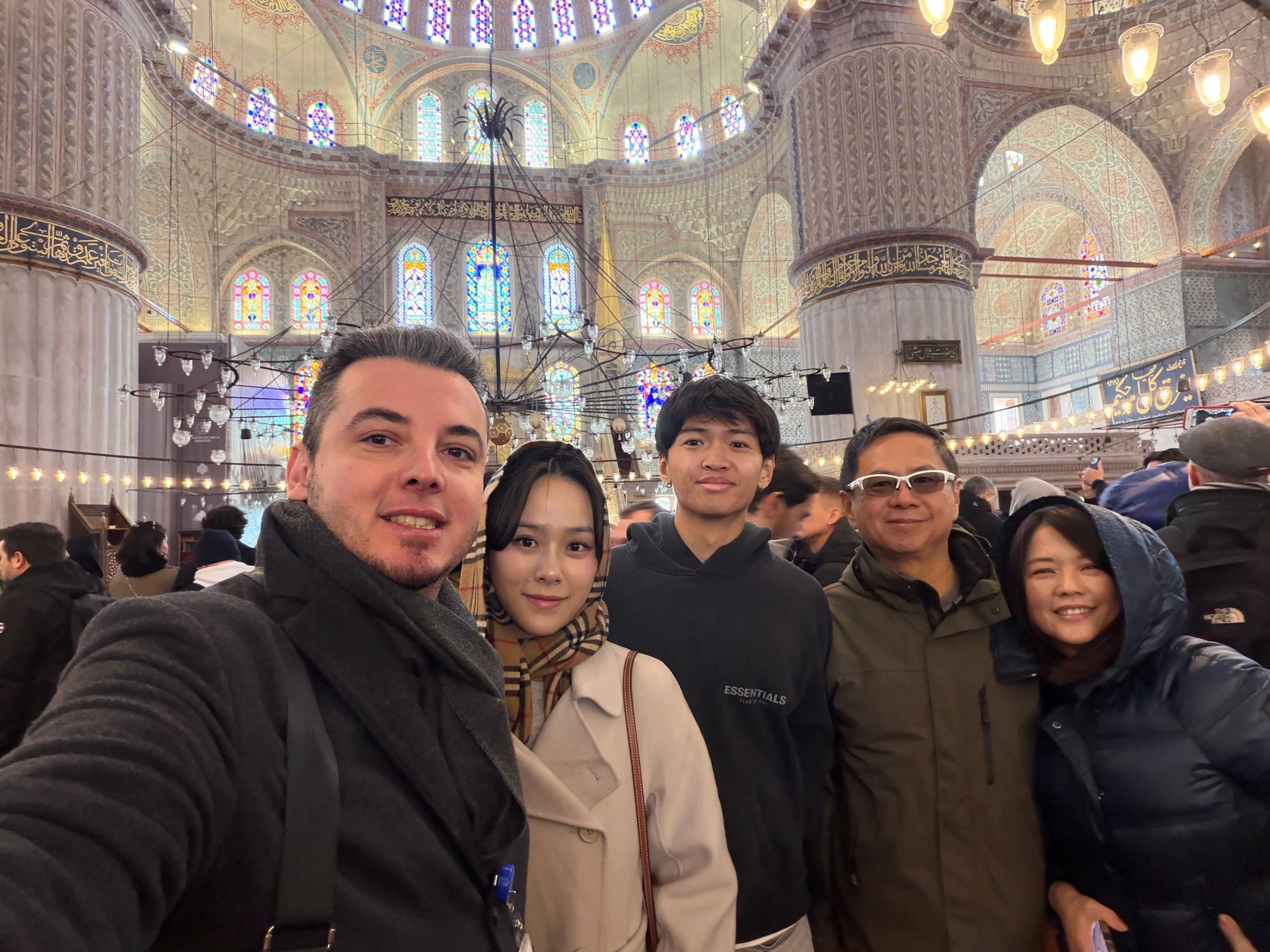 Tour guests inside the Blue Mosque under stained glass windows, Istanbul