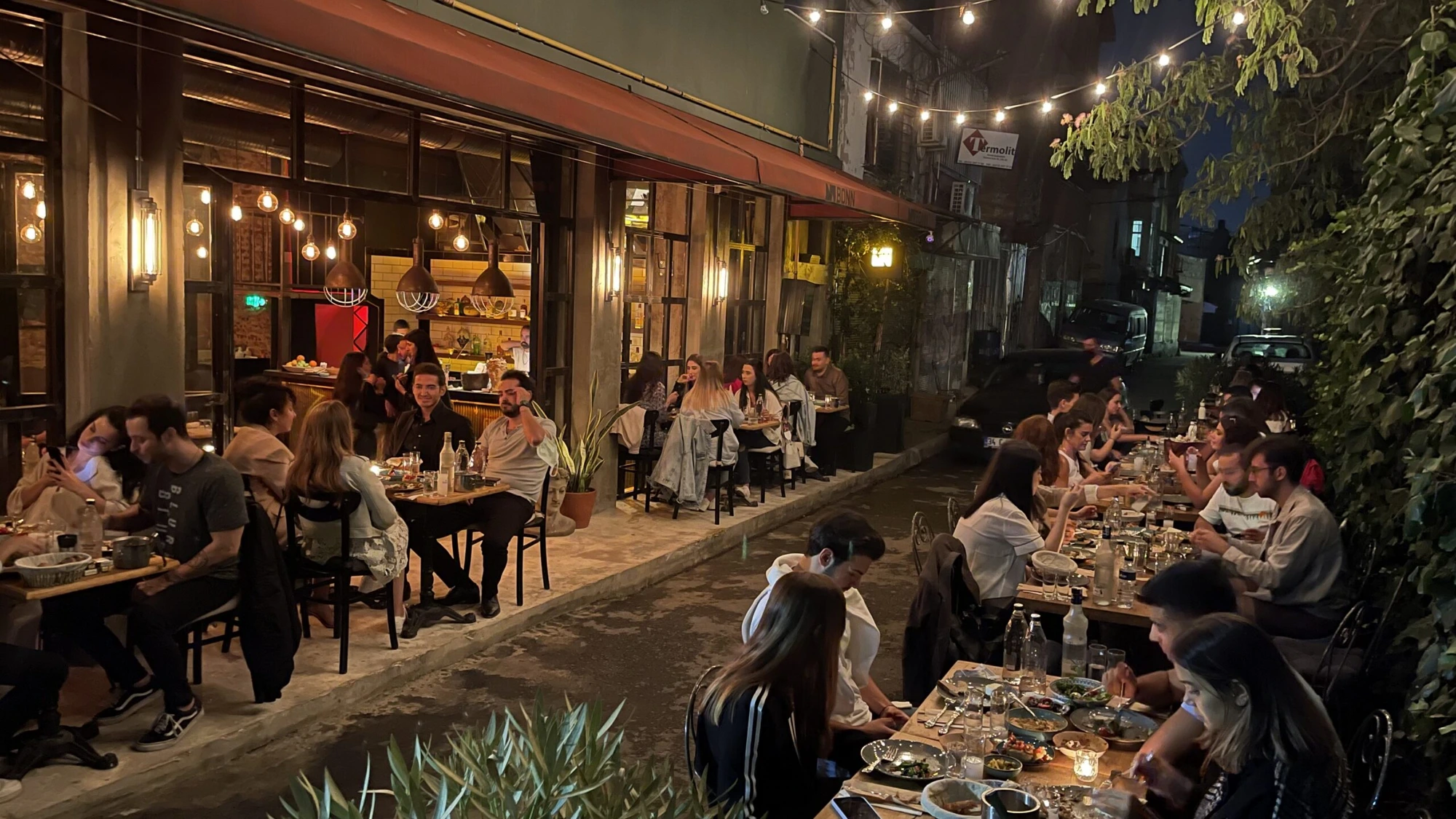Mumhane Caddesi at night — outdoor tables under string lights as the street comes alive after 8 PM