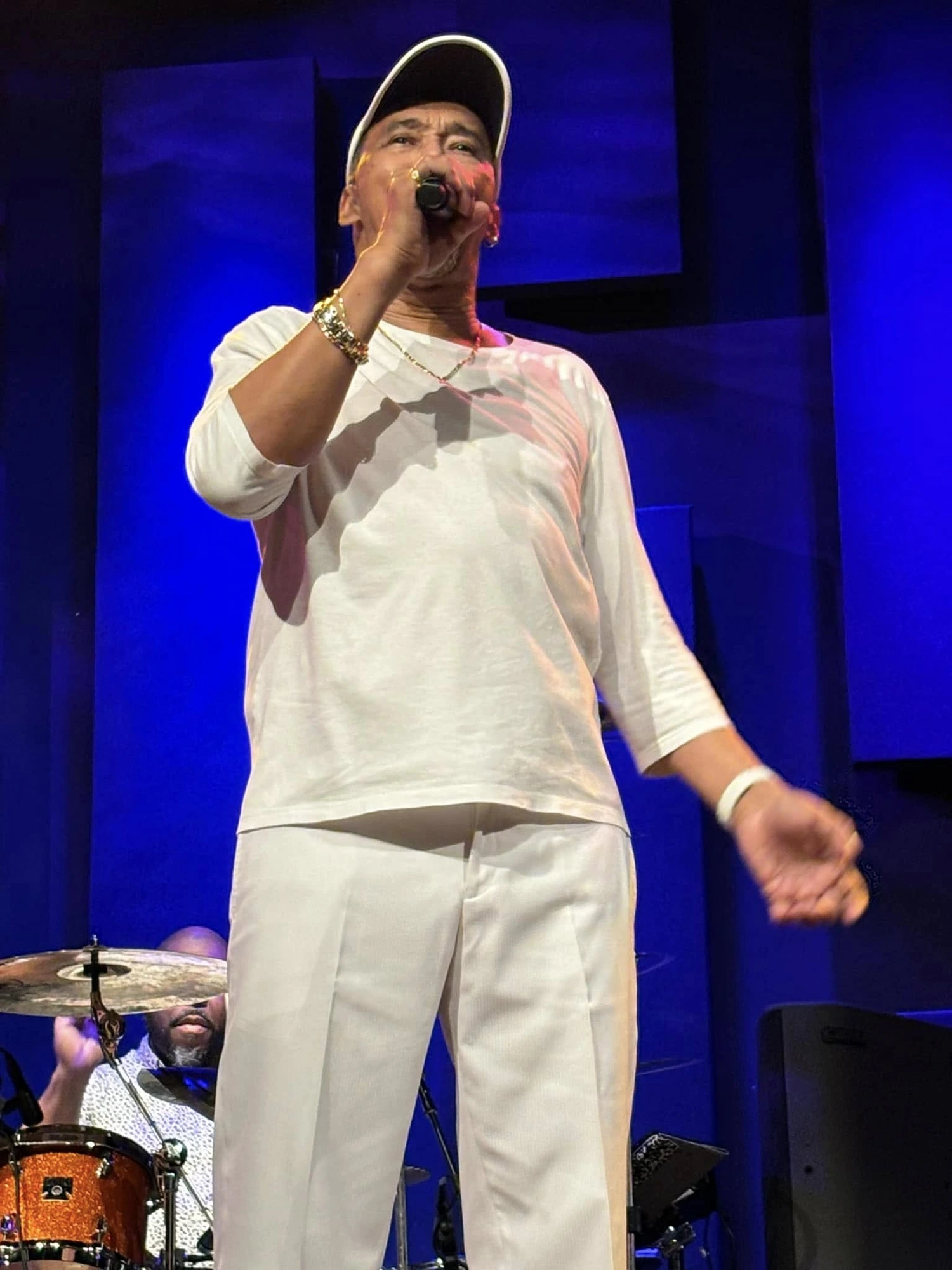 Lead vocalist performing in all white on a blue-lit stage