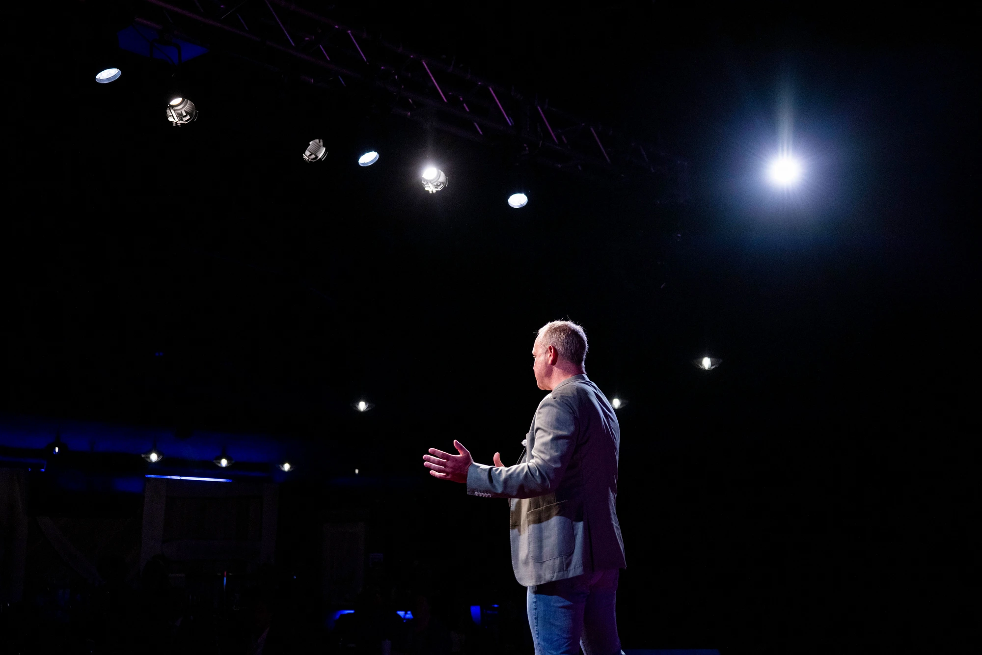 Mike DeJong on a dark stage under dramatic lighting
