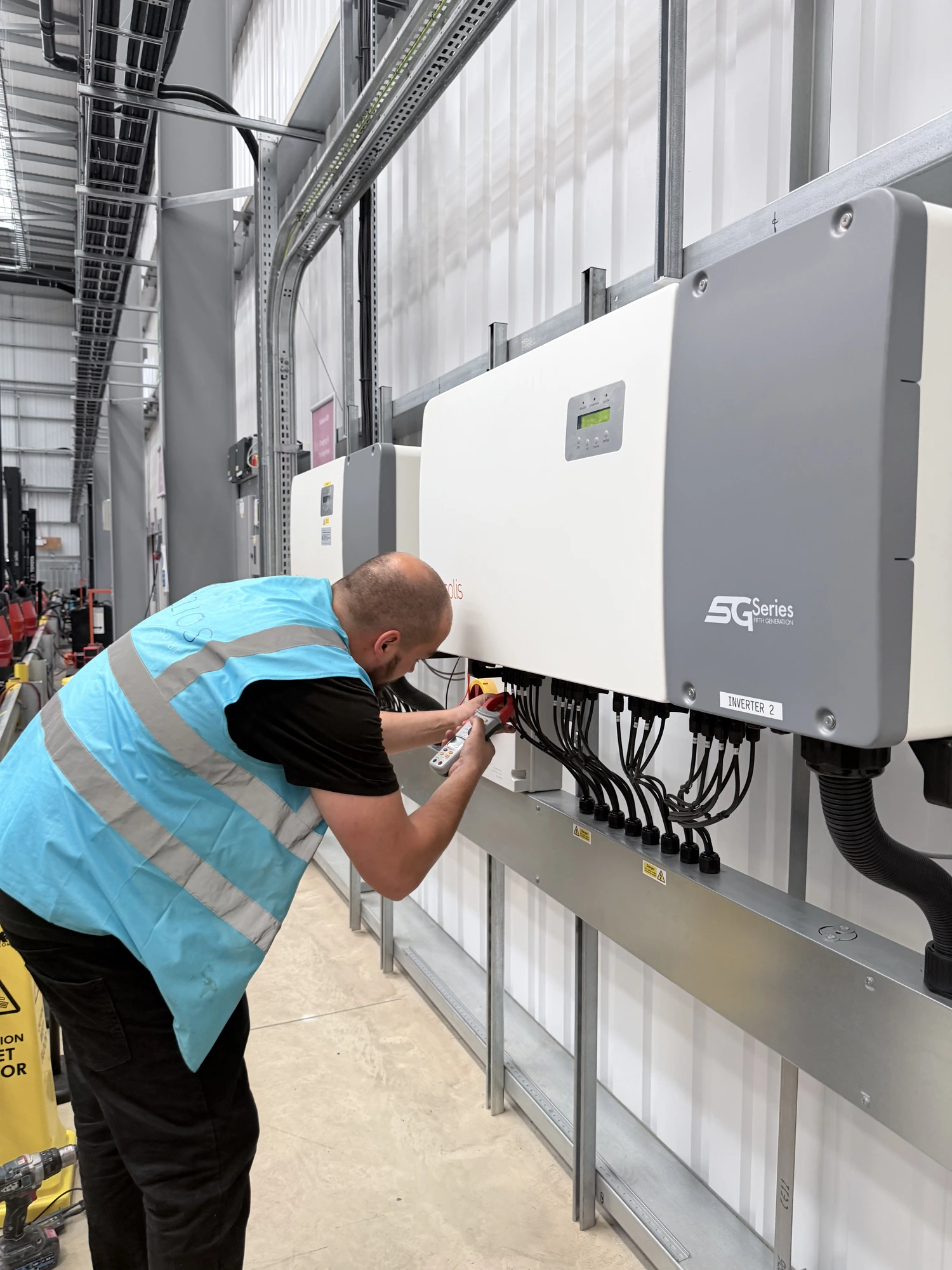 Engineer servicing commercial solar PV inverters at Hotel Chocolat warehouse