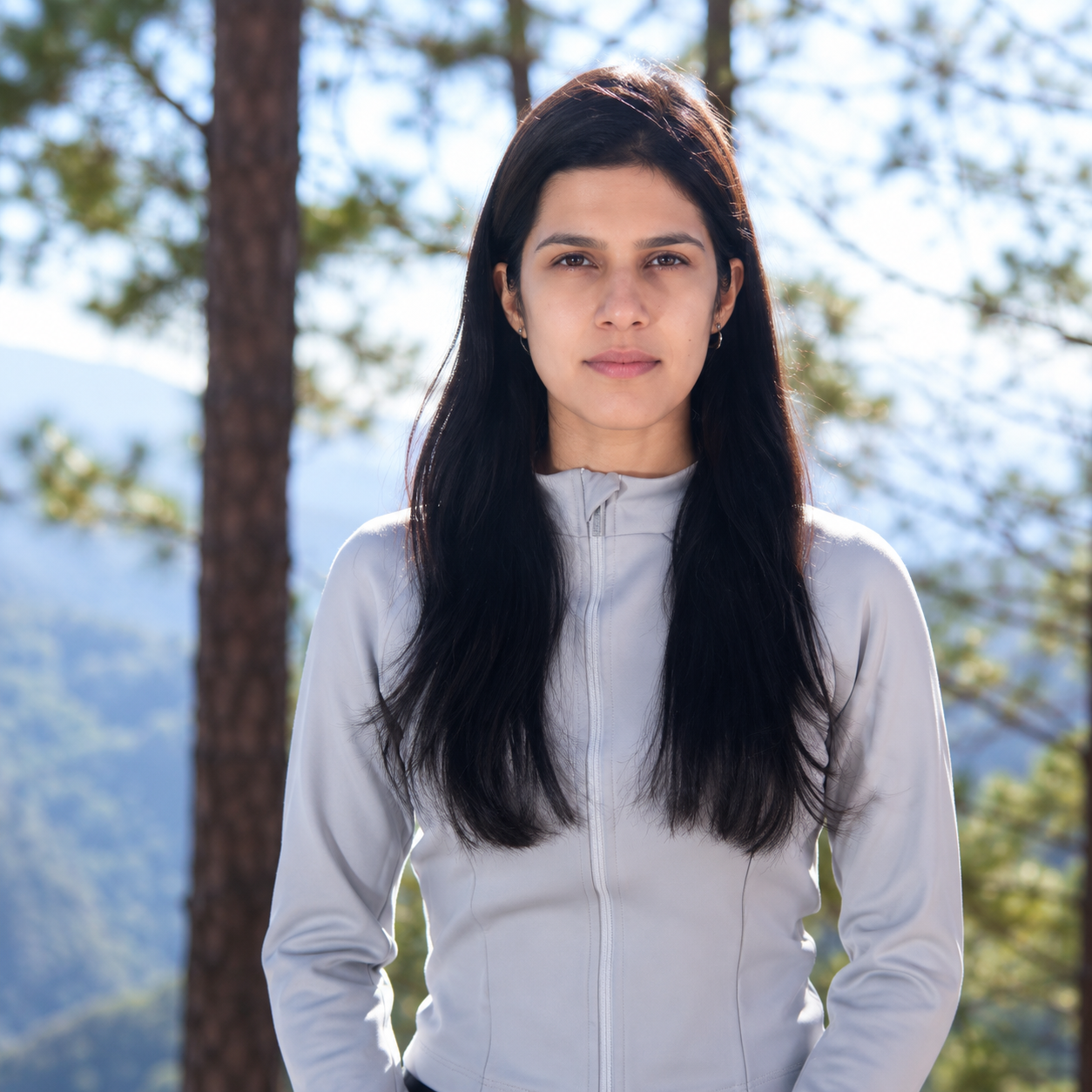 Priyanka Pahwa standing among pine trees in the mountains